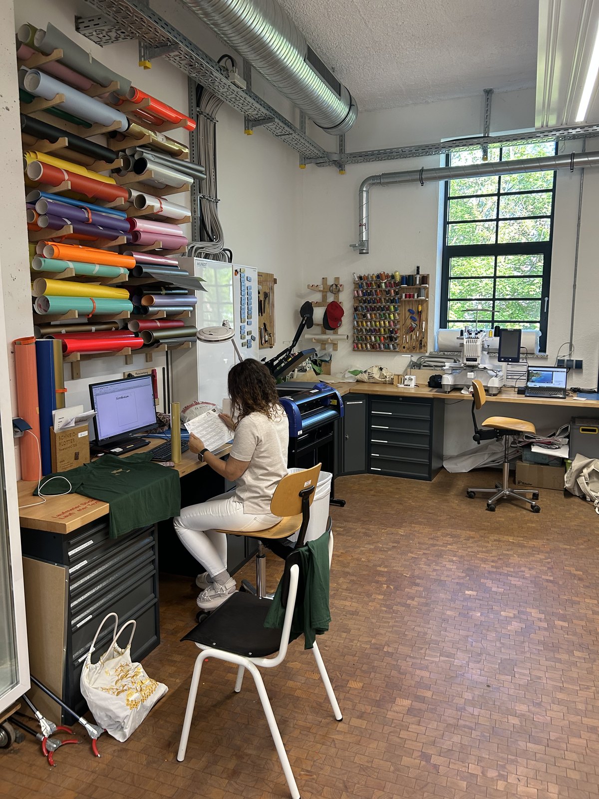 A print studio with rolls of vinyl, machines, and a t-shirt being prepared at the workbench.