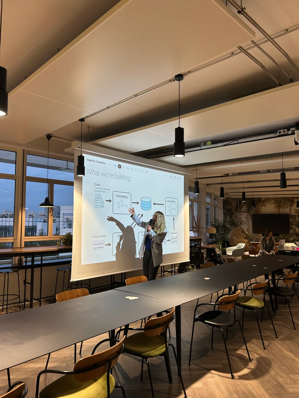 A speaker presenting adaptive translation research at Women in AI Social.
